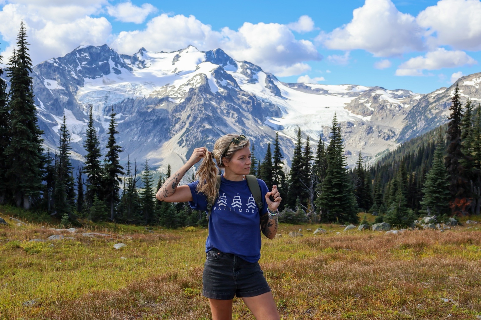 Hannah standing in an alpine meadow with mountains behind her